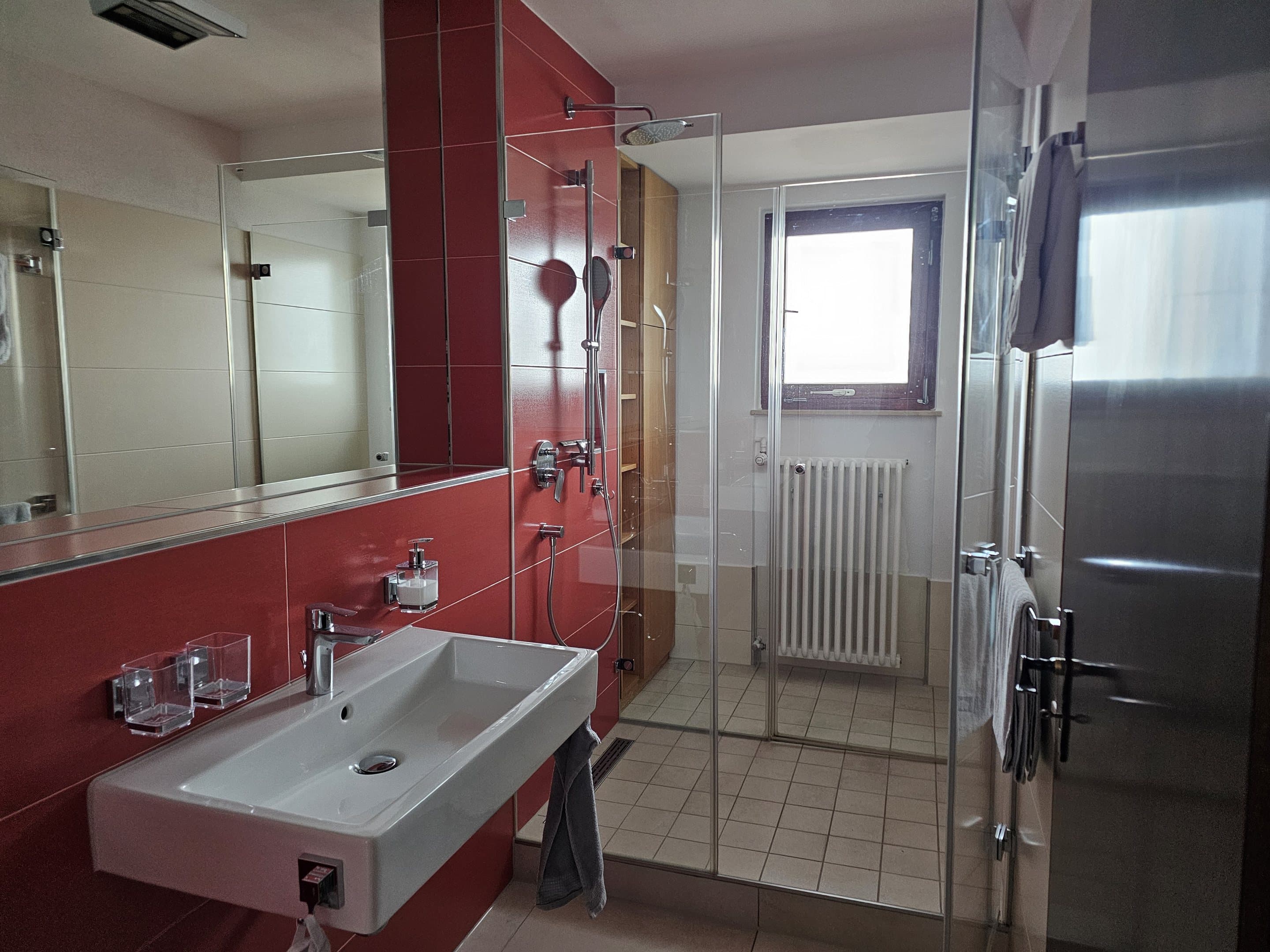 Badezimmer der Ferienwohnung mit Waschbecken, Regendusche und Spiegel